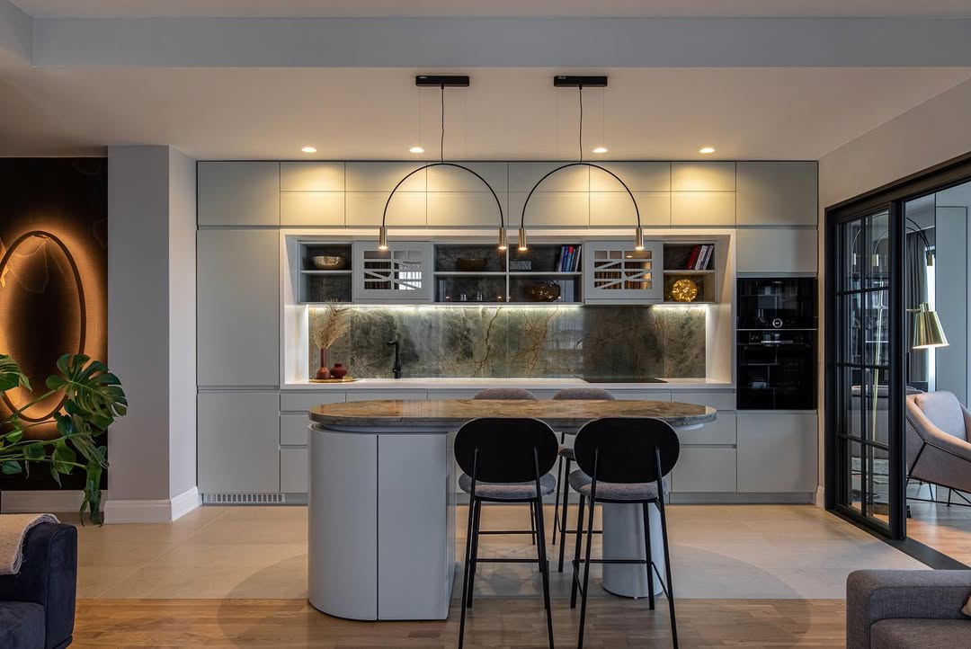 Luxurious kitchen featuring large rounded island and cool stools