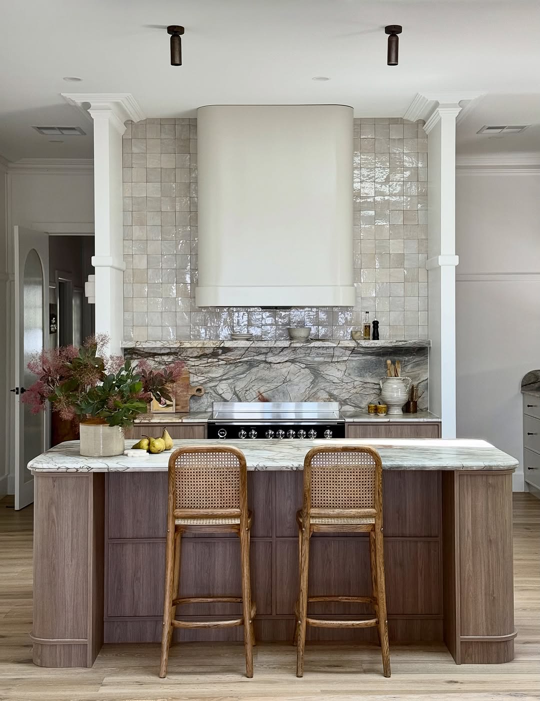 Luxurious kitchen featuring large rounded island and cool stools