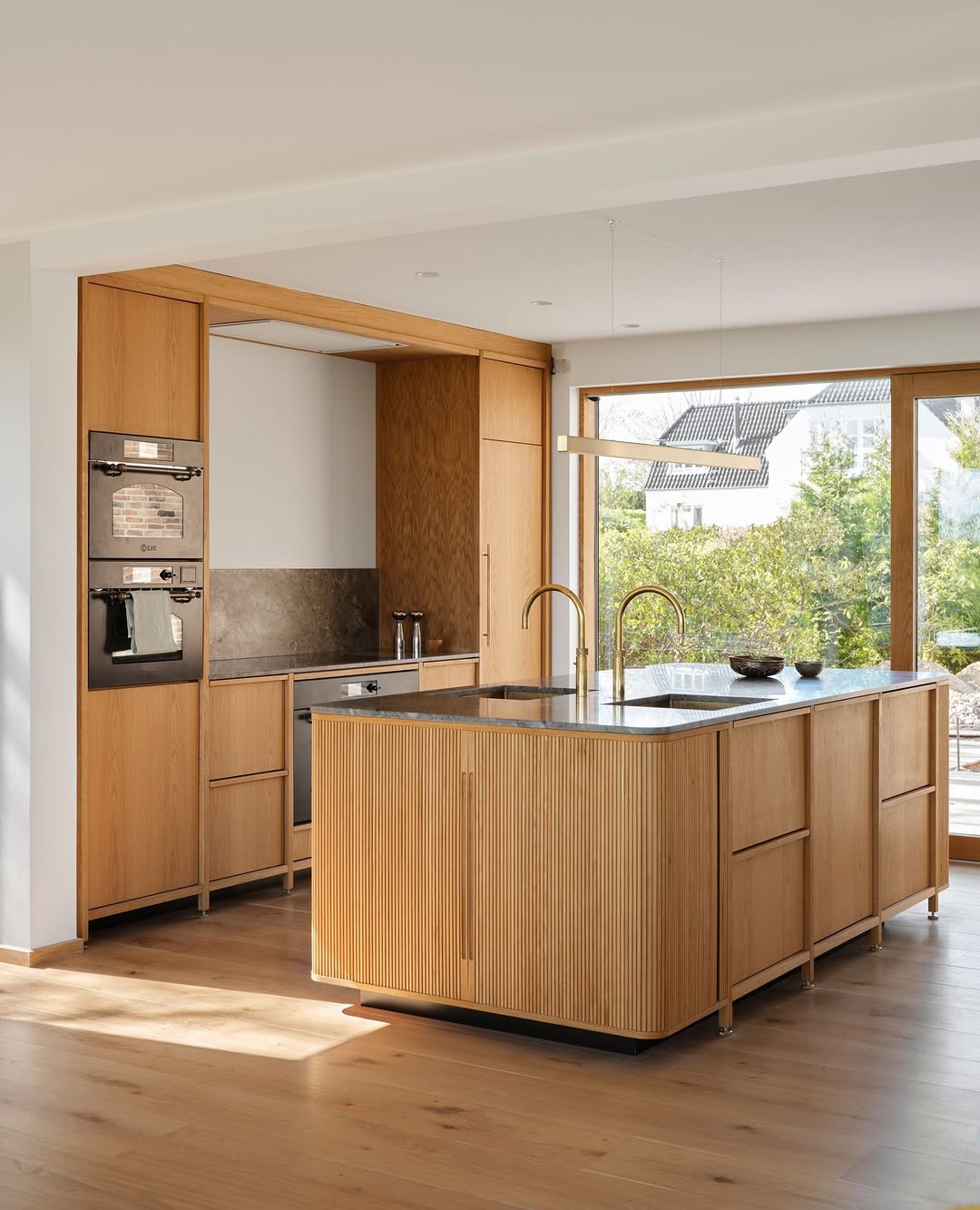 Luxurious kitchen featuring large rounded island and cool stools