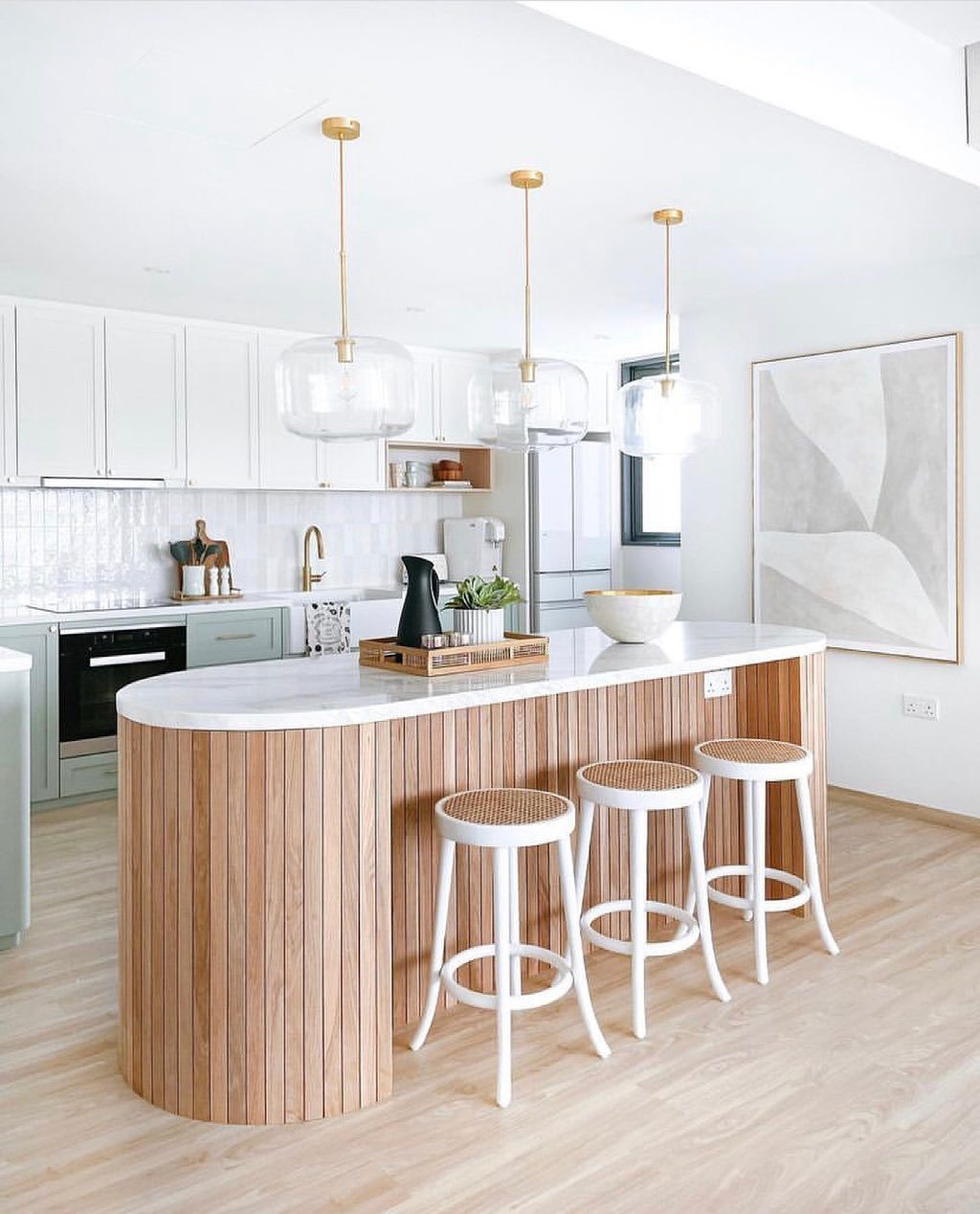 Luxurious kitchen featuring large rounded island and cool stools